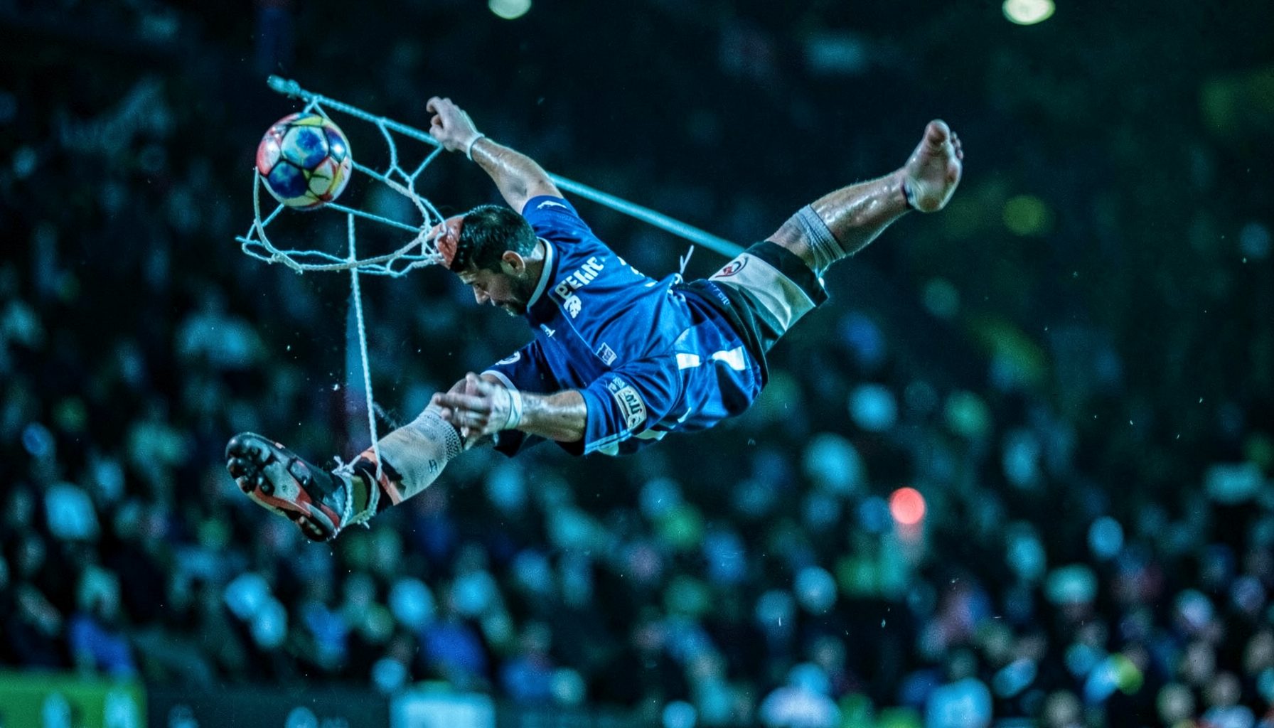 Goalkeeper diving mid-air to make a save, intense blue and green tones